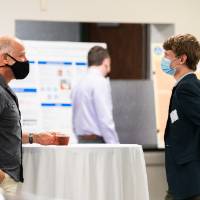 Mentor and scholar wearing masks and relaxing at table.